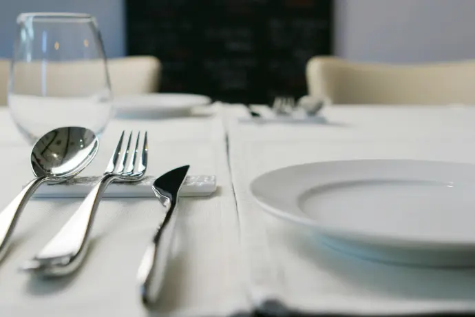 A table with a white table cloth and silverware