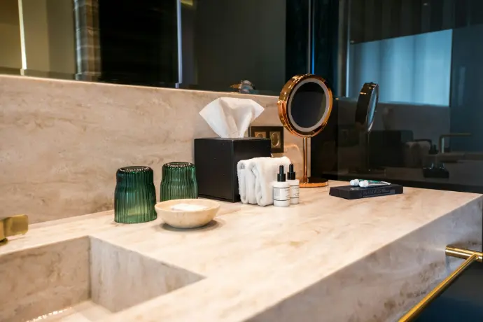 A bathroom with a sink, mirror, and soap dispenser