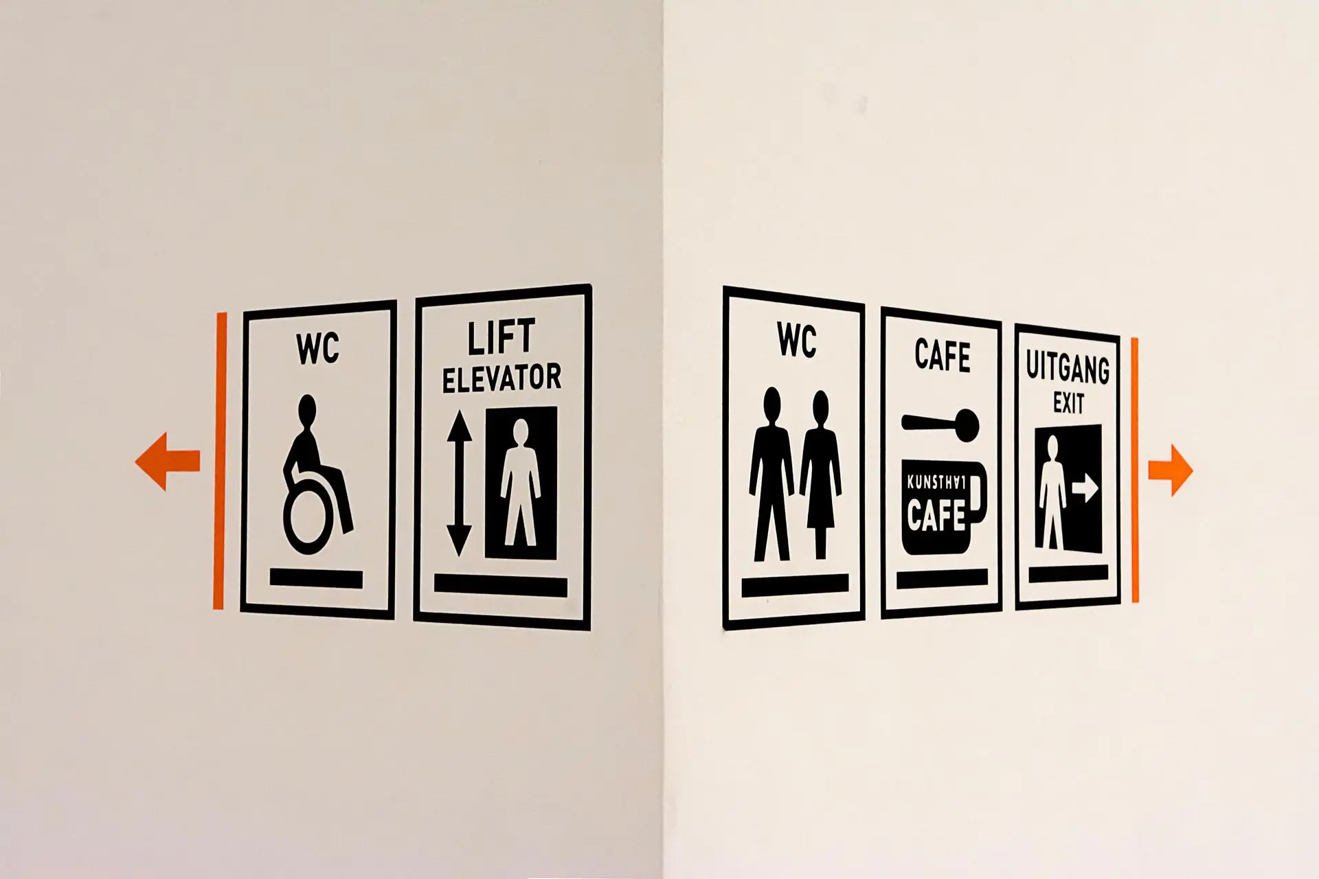 Directional Signage for Facilities and Exit Directional signage indicating restrooms, elevator, café, and exit with arrows pointing left and right.